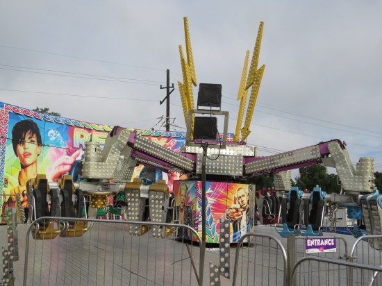 Spinning carnival ride with metal spider legs and decorative pics of Pink, Eminem, and a short-haired female celebrity I don't recognize.