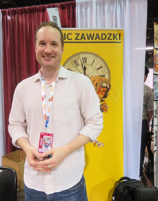 Eric Zawadzki in front of his all-yellow booth banner touting "Assorted Crisis Events".