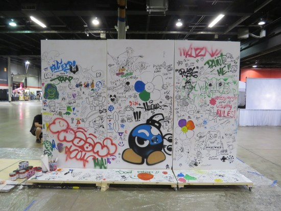 Other side of same wooden wall with random graffiti and scribbles all over it.