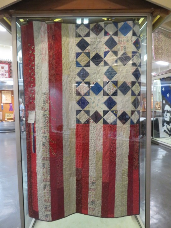hanging US flag quilt with the stars replaced by Native-looking star patterns.