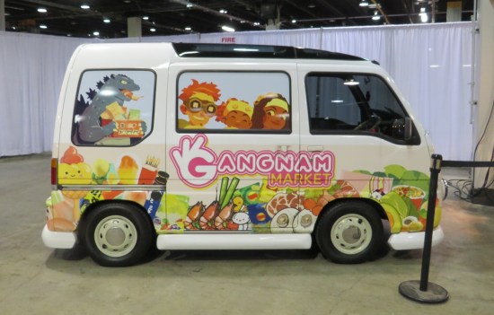 Cutesy white minivan with painted side images of Asian children, store logo, and knockoff Godzilla.