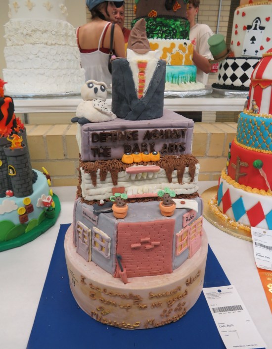 Very tall cake with various Harry Potter motifs including a Sorting Hat topper.