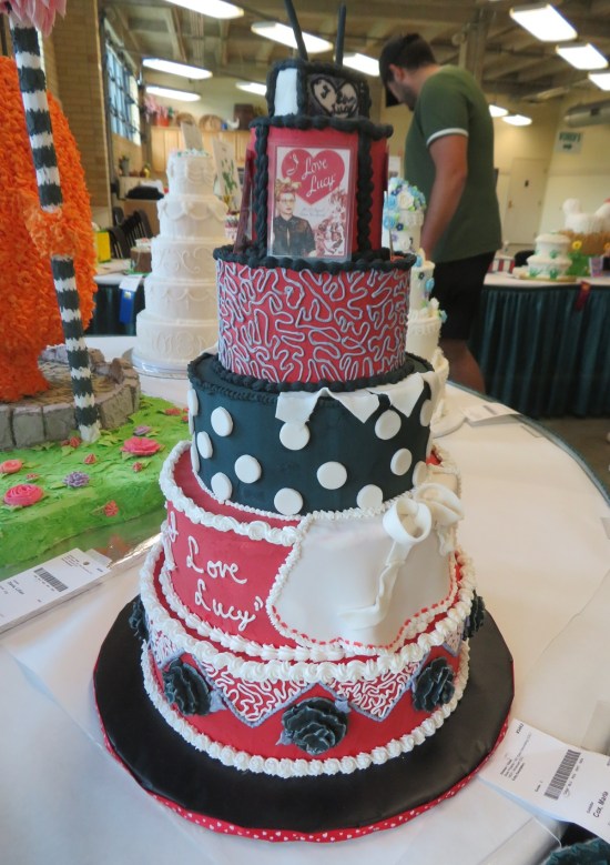 Cake with Lucille Ball dress patterns, photo of her, and the words "I Love Lucy" written on one side.