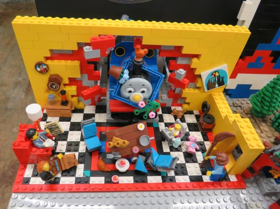 Lego Thomas the Tank Engine bursting through an occupied Lego living room.