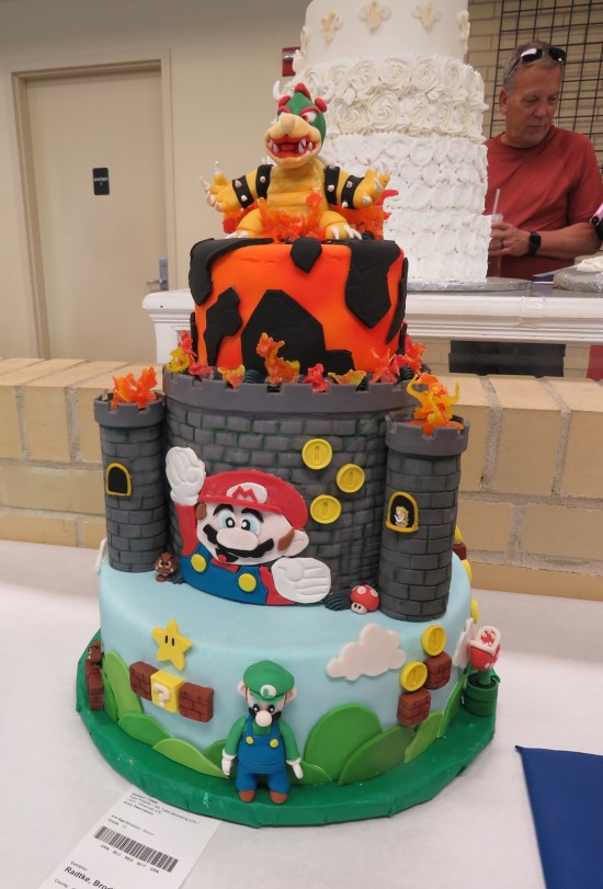 Three-layer cake with Super Mario world bottom, Bowser's castle in the middle, and lava on top.