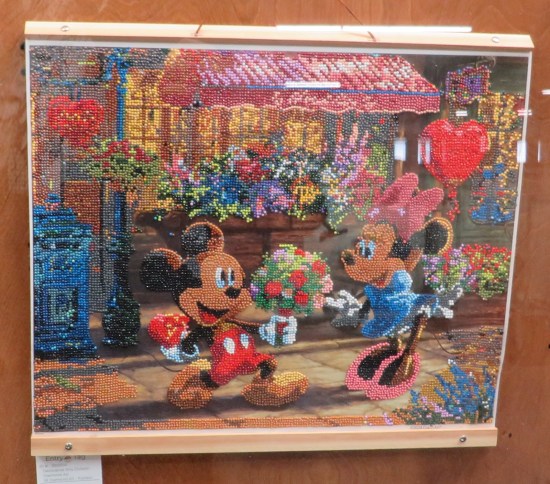 Ornate bead art of Mickey and Minnie Mouse in front of boutique with balloon, candy and flowers.