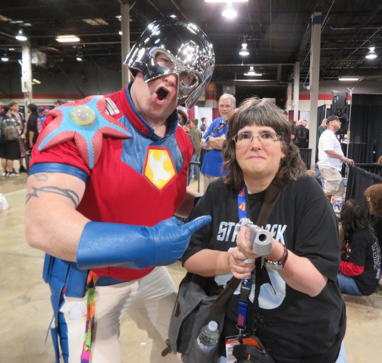 Peacemaker cosplayer lets Anne borrow his prop gun, who aims it at me!