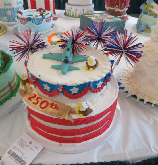 white cake with American trimmings, topped with an eagle and a fighter jet both made of icing, plus red, white and blue Koosh balls.