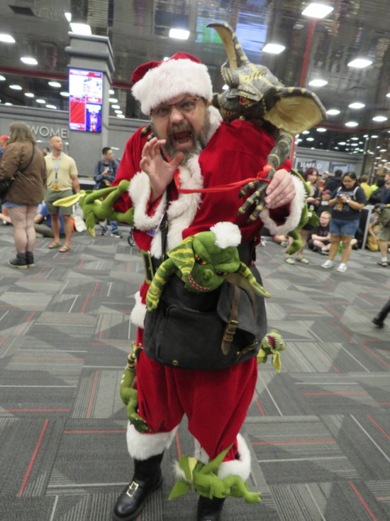 Guy in Santa Claus suit with attacking Gremlin puppets attached all over him.