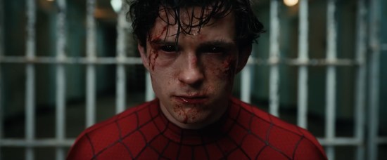 Tom Holland as Spidey standing in front of prison bars. Face is battered, eyes have turned totally black.