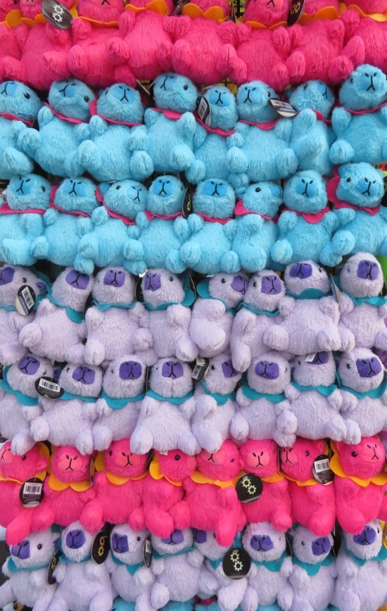 Multiple rows of stuffed rabbits in light purple, pink, or blue.