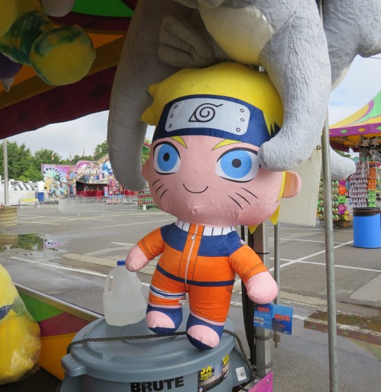 giant stuffed Naruto doll hanging at an outdoor tossing game.