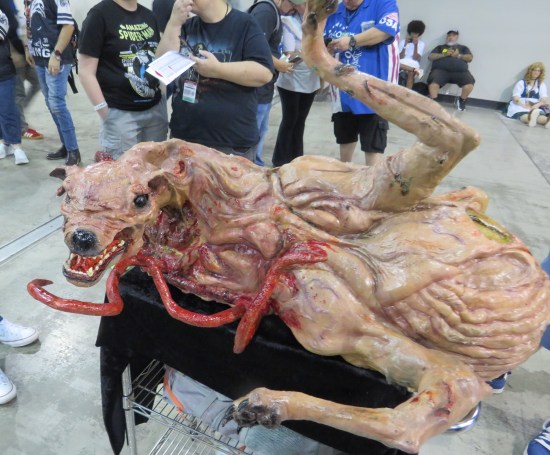 Sculpture of icky monster from "The Thing" on a cart in the middle of a convention center.