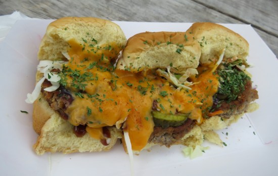 Three sliders with plenty of cheese and seasonings on a plate.