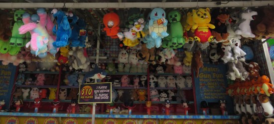 Dozens of stuffed toys hanging over a water pistol game. IPs include Kenny McCormick, Pooh, Pikachu, Squirtle, Charmander, Cookie Monster, Green Steve, and various cute animals.