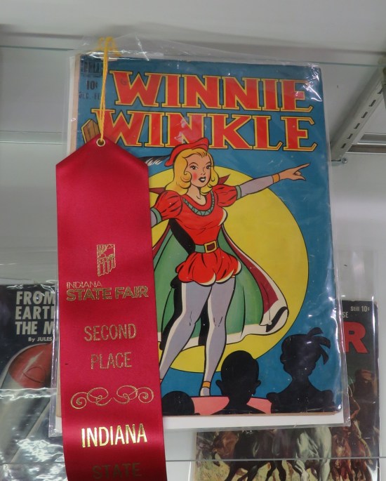 Winnie Winkle #4 cover with blonde girl dressed in vaguely Renaissance outfit on a stage. A second-place red ribbon hangs to one side of the comic.