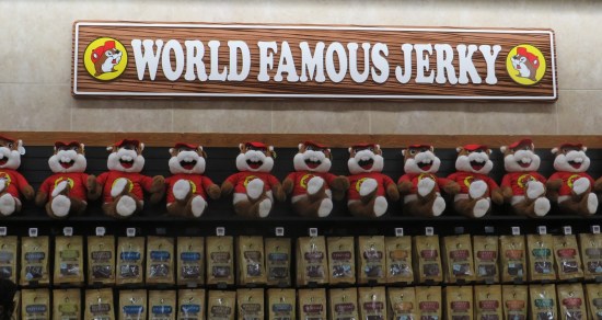 World Famous Jerky sign above a row of stuffed Buc-ee dolls with legs folded.