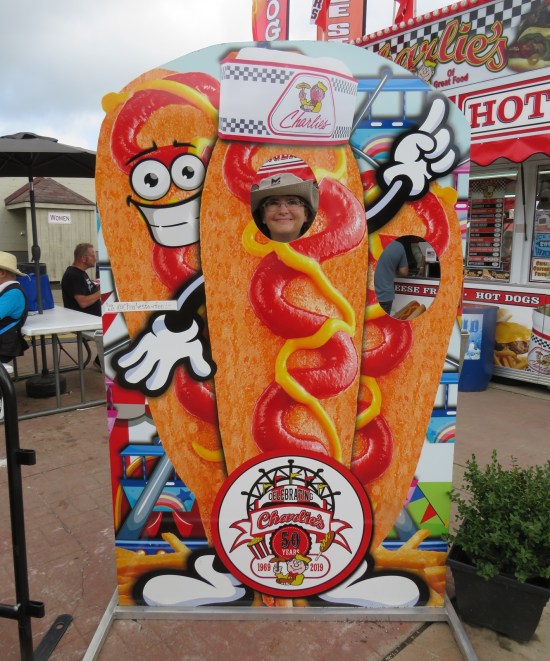 Anne sticks her face through the face hole of a corn dog standee.