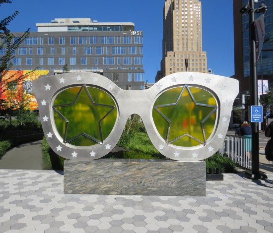 giant green glasses at the edge of a pretty city park.