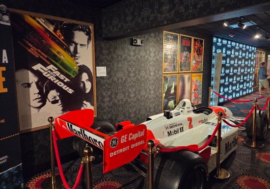 Red and white Indy car #2 in front of a Fast and the Furious movie poster.