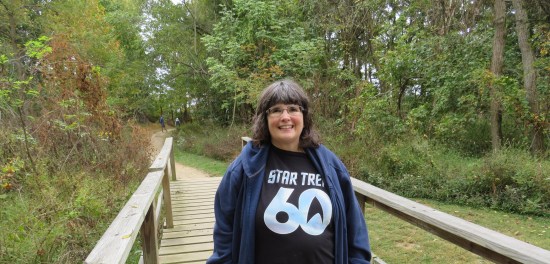 Shirt cute lady smiles on a wood bridge in a park forest.