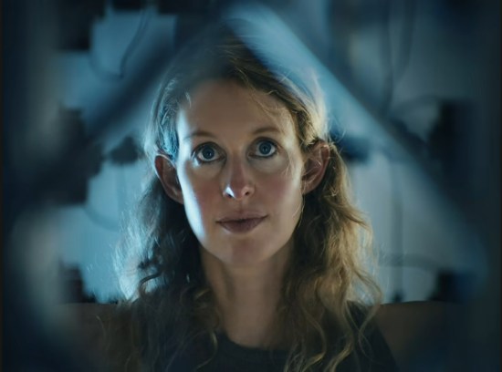 glassy-eyed Elizabeth Holmes inside a body scanning device