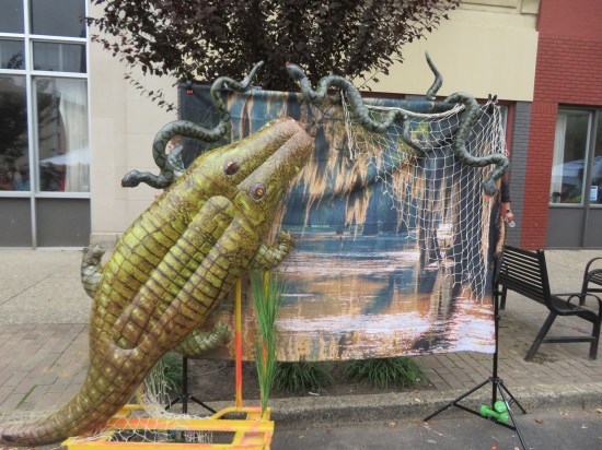 Swamp banner hung from two outdoor poles, decorated with black pythons and an alligator.