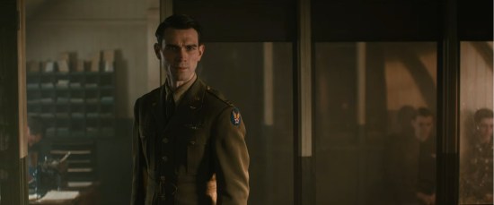KJ Apa as Jimmy Stewart in his WWII uniform, stern while an offscreen officer yells at him.