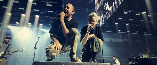 Mike Shinoda and Emily Armstrong in concert, both singing and standing on the same amplifier stack.