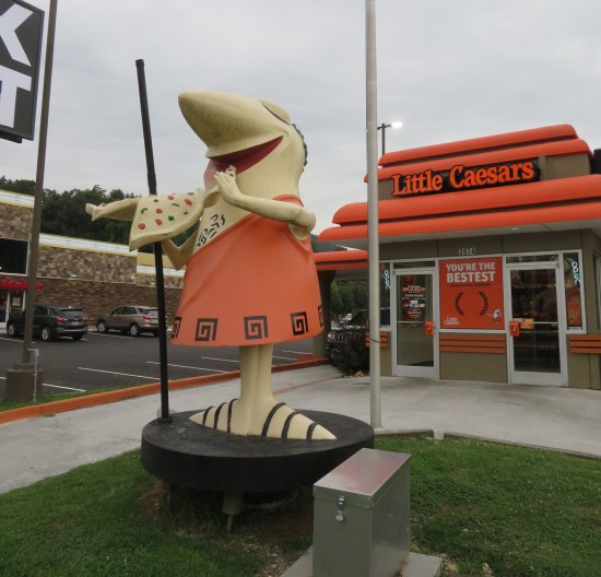 Little Caesar's Pizza store with a large statue of their mascot out front.
