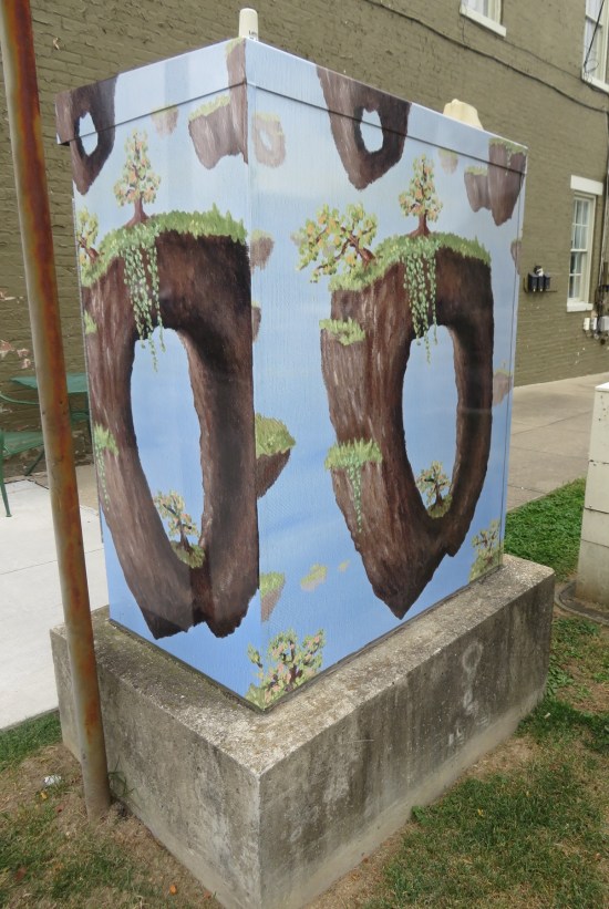 Utility box painted with science fiction islands floating midair in a sunny sky.