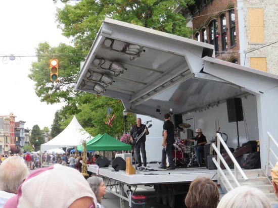Three-piece band on outdoor stage.