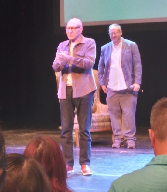 Stewart on stage, hands clasped, fuzzy.